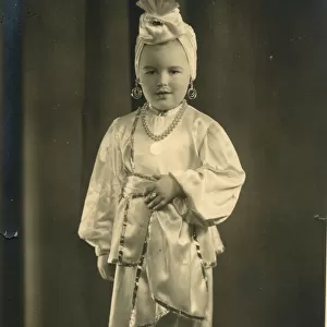 A small boy (or girl) dressed in a turban and harem pants in an Arabian Nights style