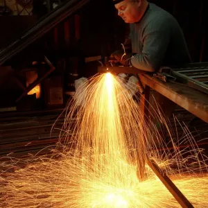 A steelworker makes a shower of sparks in his workshop A steelworker makes a shower of sparks in his workshop