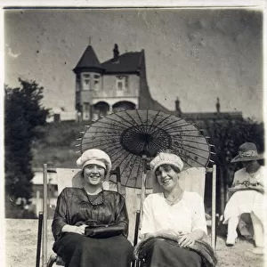 Two stylish ladies sat in deckchairs on the beach