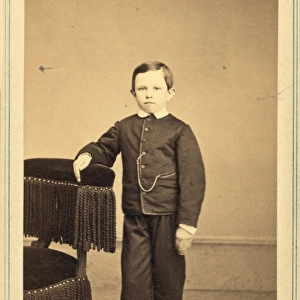 Tad Lincoln, standing, leaning against a chair