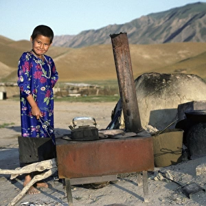 Turkmen girl - in traditional dress - boils water