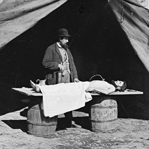 Unknown location. Embalming surgeon at work on soldiers bod