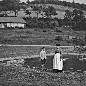 Woman and boy standing by a duckpond