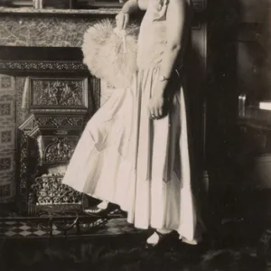 Woman in evening dress standing by a fireplace