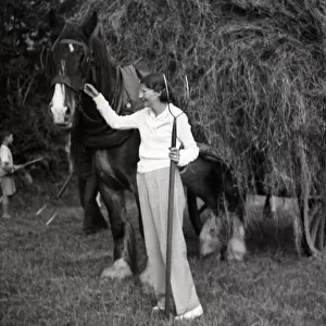Woman with pitchfork stroking a horse
