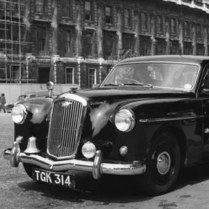 Woman police officer standing by a car, London