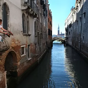Woman shakes the dirt off a pair of trainers, Venice