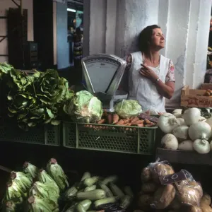 A woman stallholder behind her vegetable stall, Menorca A woman stallholder behind her vegetable stall, Menorca