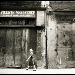Woman walking in front of boarded up shops, Valencia, Spain