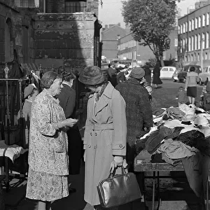 Two women chat at second hand clothes stall, London