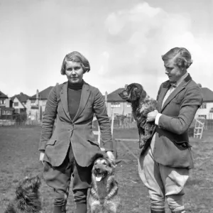 Two women with three dogs in a field