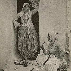 Two women smoke from a hookah pipe, Algeria