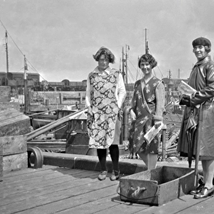Three women standing by a harbour