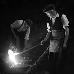Workers in foundry pouring molten metal
