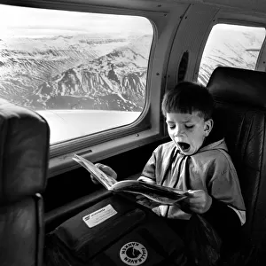 Yawning boy reads comic during an internal flight in Iceland