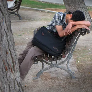 A young man sits on a park bench in Mahon, Menorca, Spain