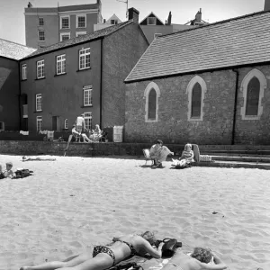 Two young women in bikinis sunbathe - Tenby Harbour, Wales