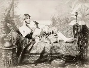 19th century vintage photograph: young woman from either Egypt or Turkey on a chaise