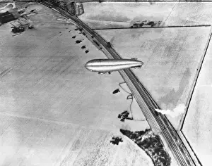 Airship Flying over Railway Tracks and a Steam Train