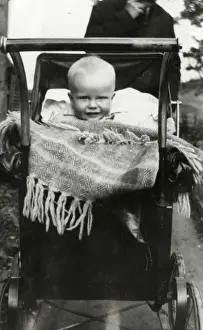 Nestled Prints: A Baby smiling out from a large Perambulator