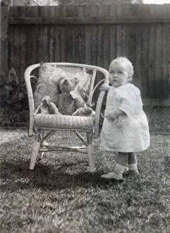 A baby toddles up to an elegant cane chair in her garden to say hello to her favourite