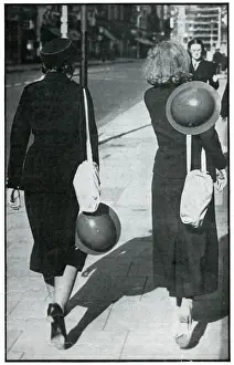 Gender Prints: Backs of two walking girls holding helmets, September 1939