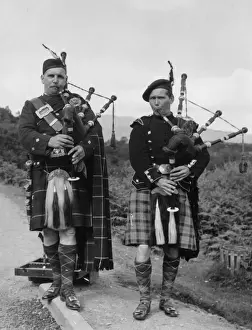 Buckle Prints: Two bagpipers on a road in the Trossachs, Scotland