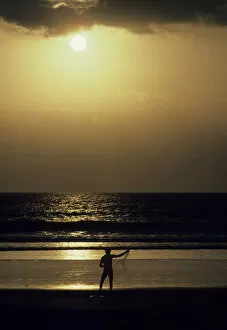 Bali fisherman silhouetted against the golden sea and sunset