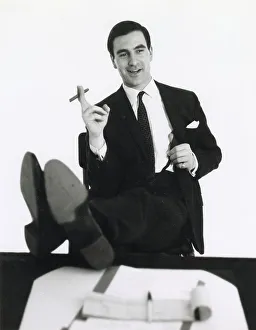 Puts Prints: A banker puts his feet up on his desk and smokes a cigar. Date: late 1960s