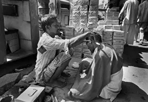 Haircut Prints: A barber squats in the street in Chandni Chouk, Old Delhi