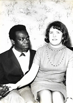 Images Dated 19th July 2016: Black man and white woman sitting on a bed holding hands