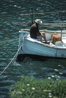 Menorca Gallery: Boatman in stern of a small open fishing boat Menorca, Spain