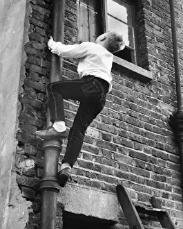 Boy climbing drainpipe on a Balham house, SW London