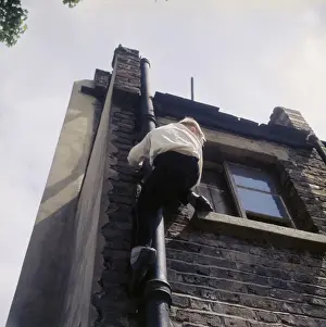 Boy climbing drainpipe on a Balham house, SW London