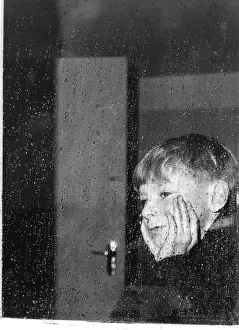 Boy looking through a window on a rainy day