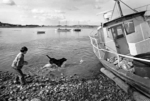 Galloway Prints: A boy plays with a black dog in the harbour at Garlieston