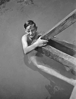 Boy swimmer holding on to wooden beam