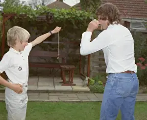 Boy and young man playing conkers in the garden