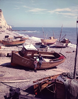 Two boys with boats on a pebbly beach, Devon