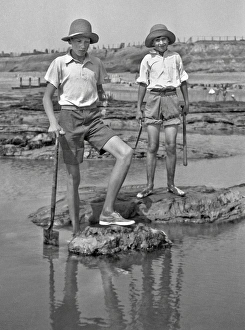 Two boys exploring rock pools at the seaside