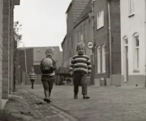Two boys with a football in the street