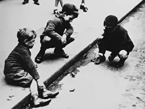 Gutter Prints: Three boys playing marbles in the gutter