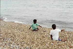 Two British Caribbean boys playing with stones on Brighton