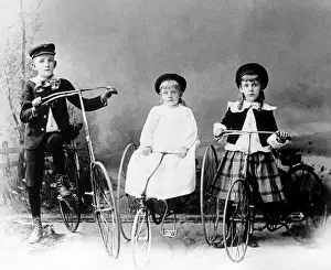 Three children posed with bicycle and tricycles in America