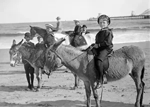 Children riding donkeys on a beach, probably in Atlantic Cit