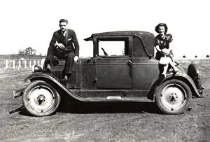 Automobilia Prints: Couple pose for a picture on a small car
