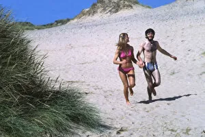 Couple running on a beach, West Country