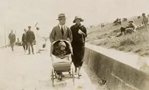 Grassy Collection: Couple strolling along the seafront with toddler in buggy