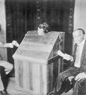 Margery in a fraud-proof box devised by Richardson and Houdini ; the latter is holding her left hand, her other hand is held by Walter Prince Crandon & Houdini