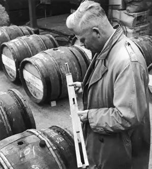 Customs Official checks the volume of wine in a barrel